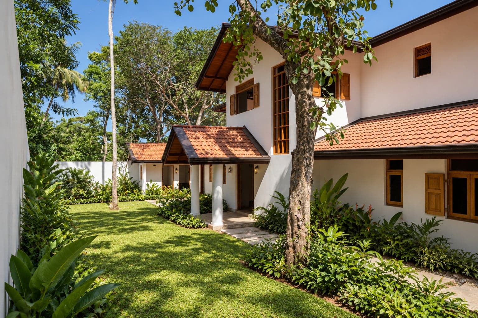 The entrance porch and side lawn of Kottamba Kanda under a kottamba tree (architectural render)